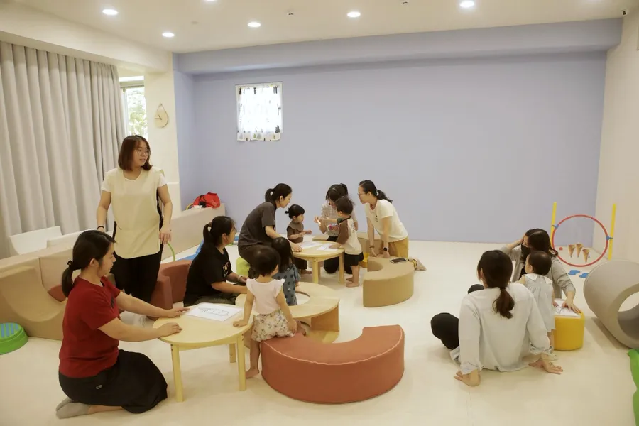 幾位家長帶著小孩坐在軟墊上上課